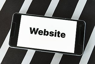Das Bild zeigt ein Smartphone, auf dem das Wort "Website" zu lesen ist.