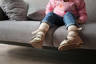 Ein Kind sitzt auf einem Sofa.