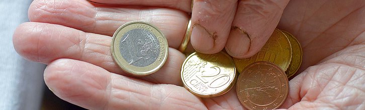 Eine Hand mit wenigen Münzen wird gezeigt